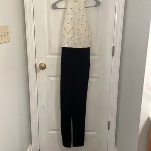 Women jumpsuit, white studded high neck halter top, black straight leg pant.